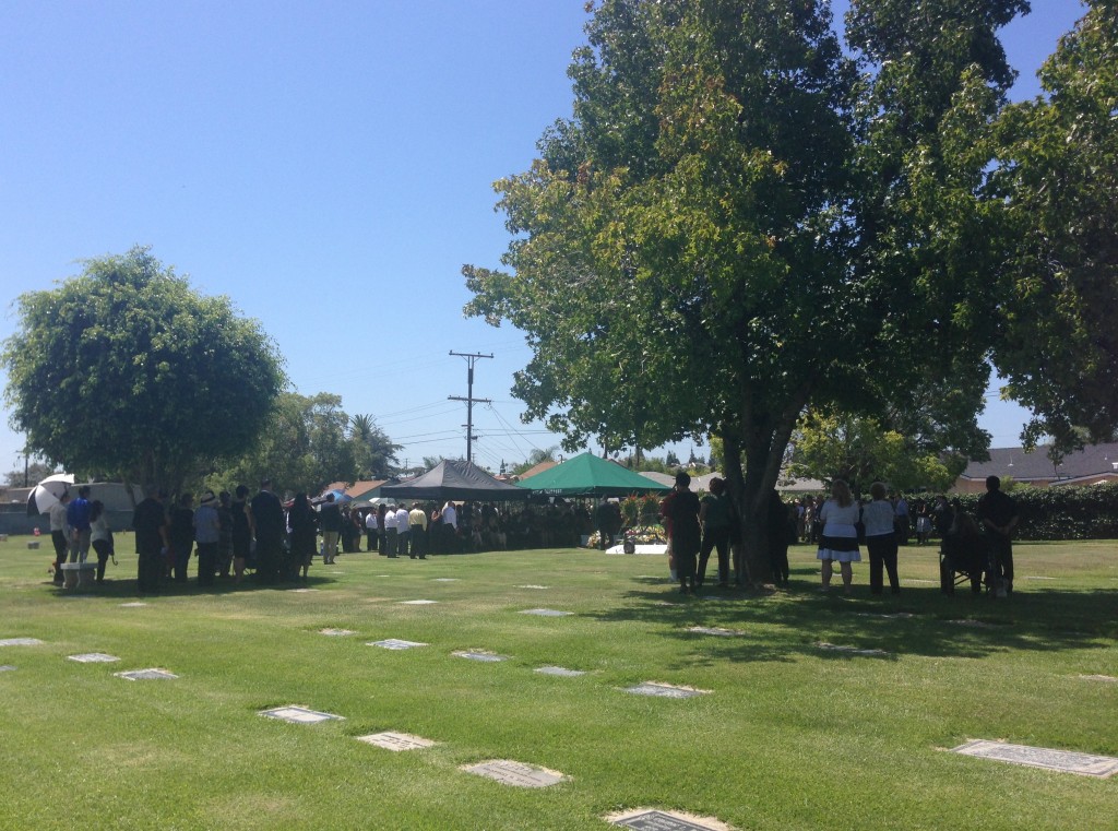 Long shot of Hoagy's mourners near the tent, and some under the shade trees.