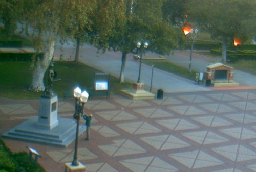 In a shot from the campus webcam, Dec. 1 at 7:05 a.m., a man in a teal coat apparently offers a small child as a blood sacrifice to Tommy Trojan in the hope of securing divine aid to defeat Stanford in this weekend's Pac-10 Championship game.  OJB doubts that even that would work.  In any event, we're not even entirely convinced that he's holding up a child at all.  The ways of USC are mysterious to us.